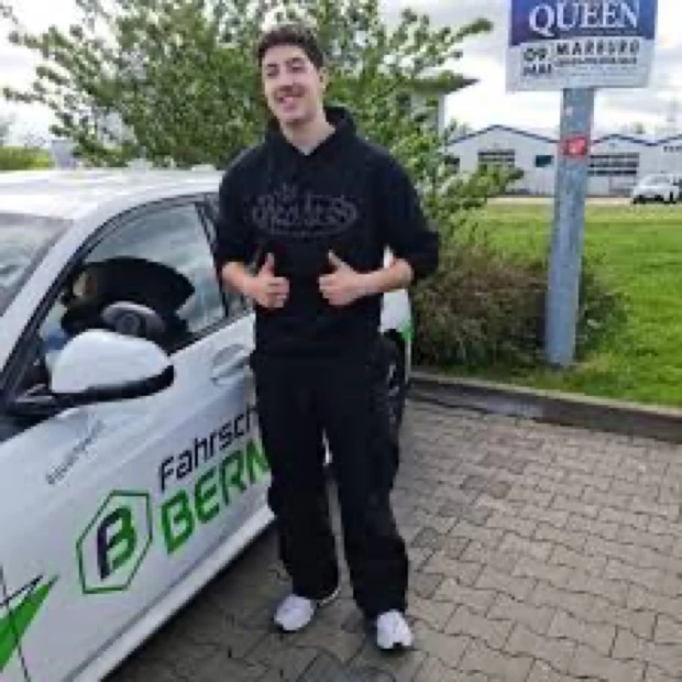 Frisch bestandener Fahrschüler vor dem Auto der Fahrschule Bernert