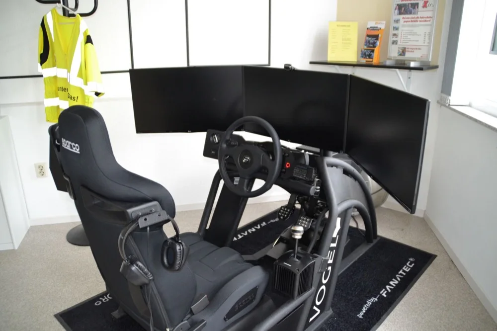 Der Vogel-Fahrsimulator der Fahrschule Bernert mit Rennsitz, Lenkrad und drei Bildschirmen